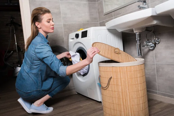 Housewife putting clothing into washing machine at home — Stock Photo