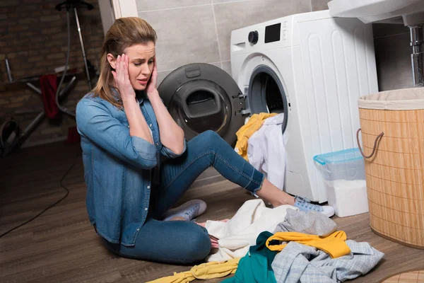 Домохозяйка смотрит на кучу одежды в стиральной машине дома — стоковое фото