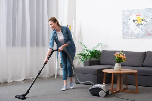 Привлекательная женщина с пылесосом уборка комната на дому — стоковое фото