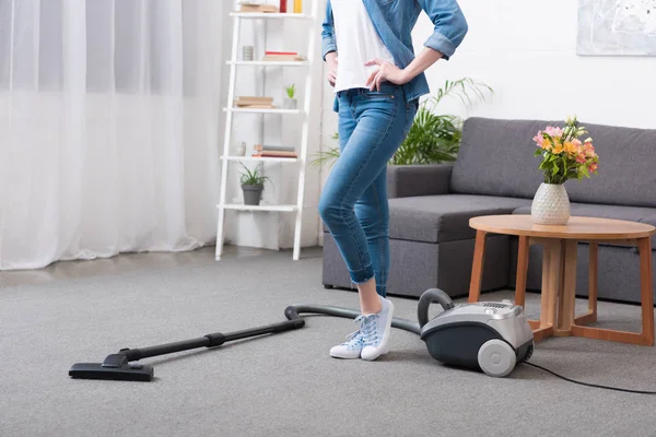 Vista parcial de la mujer de pie akimbo en la habitación ingenio aspiradora - foto de stock