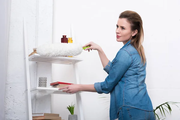 Vista laterale della donna in abbigliamento casual con pulizia della polvere spazzola pulizia casa — Foto stock