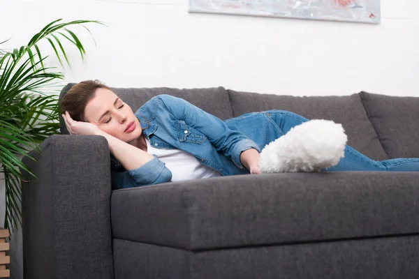 Müde Frau mit Staubsaugerbürste in der Hand schläft zu Hause auf Sofa — Stockfoto