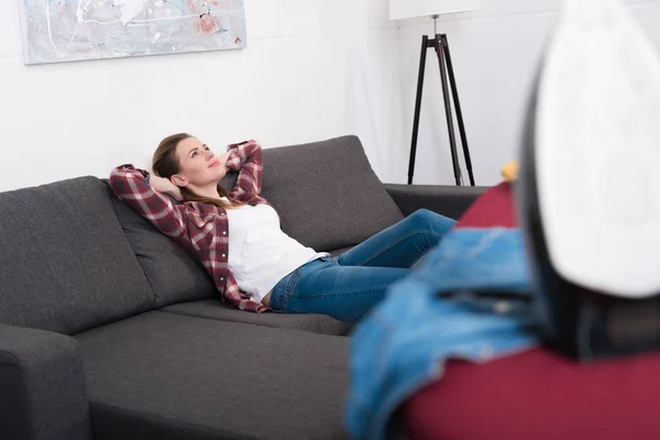 Foyer sélectif de la femme reposant sur le canapé à la maison avec fer à repasser devant — Photo de stock