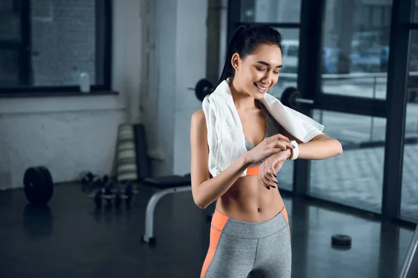 Young happy sportswoman using smartwatch to check activity at gym — Stock Photo