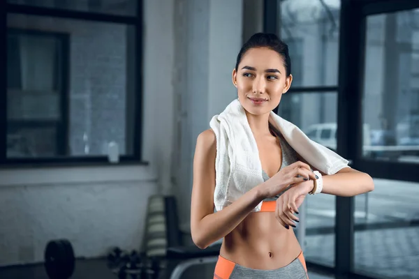 Young sporty woman using smartwatch to check activity at gym — Stock Photo