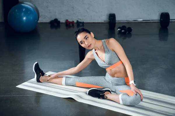 Молодая спортсменка делает боковой изгиб на коврике для йоги в тренажерном зале — стоковое фото