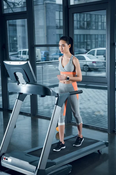 Young athletic sportswoman running on treadmill at gym — Stock Photo