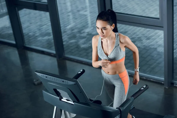 High angle view of young athletic sportswoman running on treadmill at gym — Stock Photo