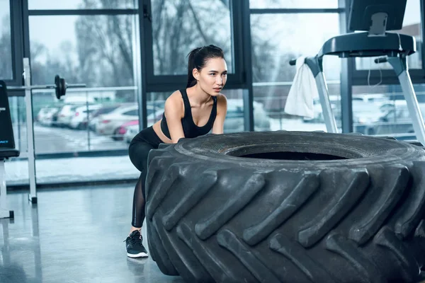 Attrayant sportif femme flipping roue d'entraînement à la salle de gym — Photo de stock