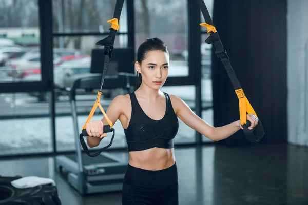 Jeune femme en forme travaillant avec des bandes de résistance à la salle de gym — Photo de stock