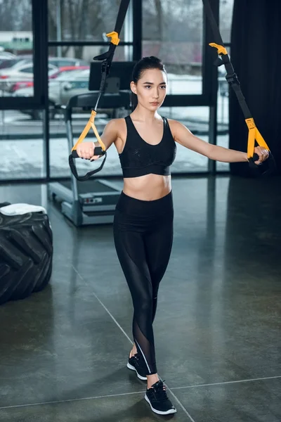 Sportliche junge Frau trainiert mit Widerstandsbändern im Fitnessstudio — Stockfoto