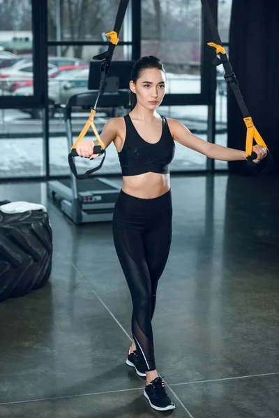 Jovem mulher esportiva trabalhando com bandas de resistência no ginásio — Fotografia de Stock