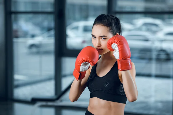 Joven boxeadora en guantes en el gimnasio mirando a la cámara - foto de stock