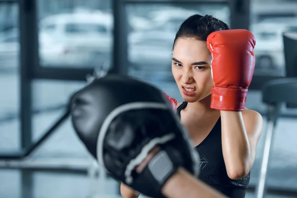 Boxeuse faisant de l'exercice avec son entraîneur au gymnase — Photo de stock