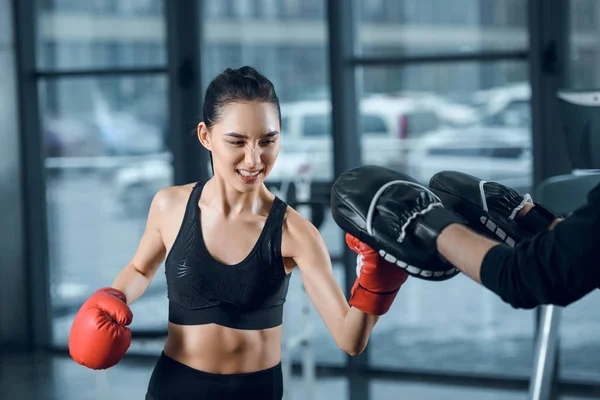 Esportivo jovem boxeador do sexo feminino exercitando com treinador no ginásio — Fotografia de Stock