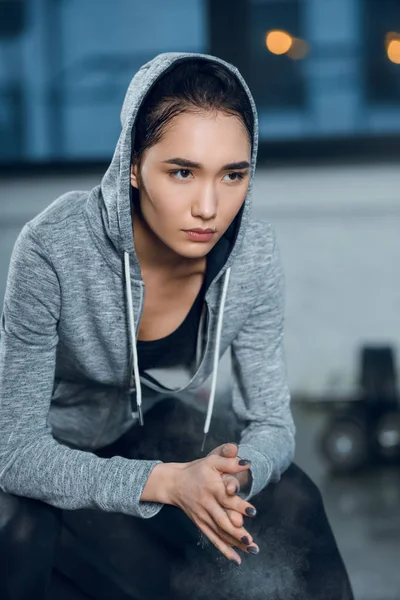 Молодая женщина, хлопающая в ладоши тальком перед тренировкой в спортзале — стоковое фото