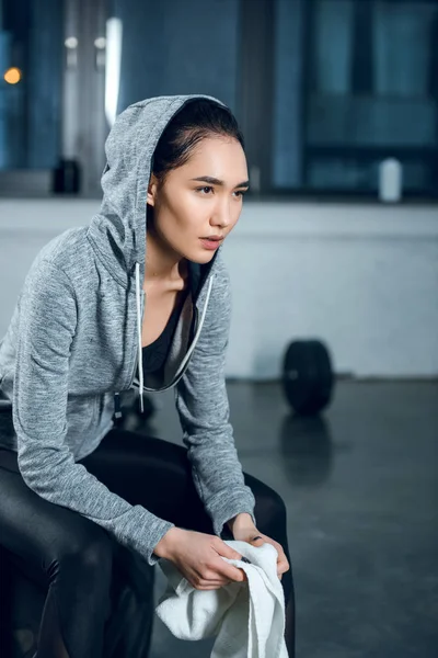 Junge sportliche Frau mit Kapuze sitzt im Fitnessstudio — Stockfoto