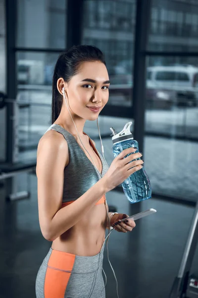 Junge, fitte Frau mit Wasserflasche im Fitnessstudio — Stockfoto