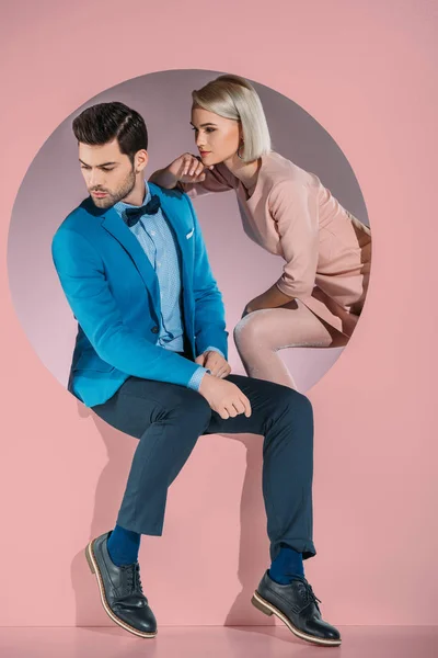 Красивая пара в стильной одежде, смотрящая вниз на розовый — стоковое фото