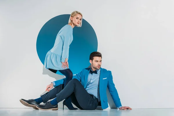 Attraktives stylisches Paar sitzt und schaut in die Kamera auf grau — Stockfoto