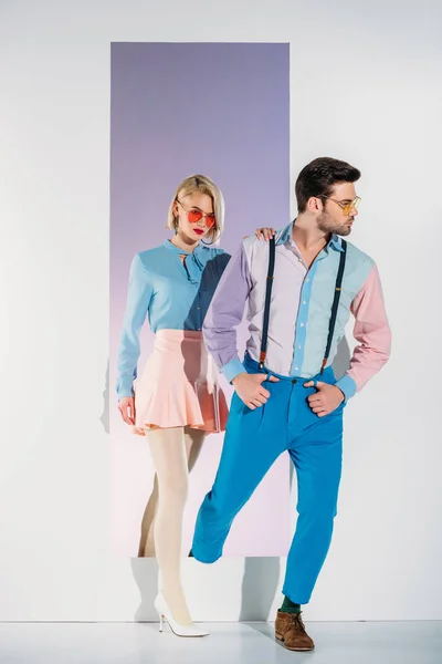 Attraktives Paar in modischen Kleidern, die durch Rahmen auf Weiß gehen — Stockfoto