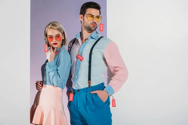 Atractiva pareja en ropa de moda con etiquetas de venta aisladas en blanco - foto de stock