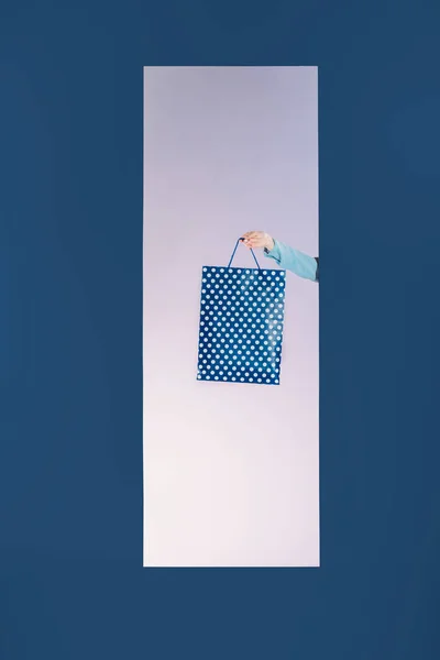Обрізане зображення дівчини, що тримає сумку в рамці ізольовано на синьому — стокове фото