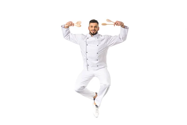 Young male chef holding utensils and smiling at camera isolated on white — Stock Photo