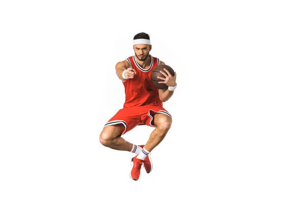 Молодий баскетболіст тримає м'яч і вказує на камеру з пальцем ізольовано на білому — стокове фото