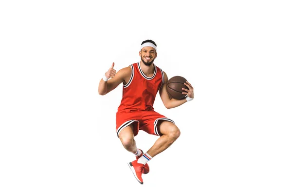 Glücklicher junger Basketballspieler hält Ball und zeigt Daumen nach oben isoliert auf weiß — Stockfoto