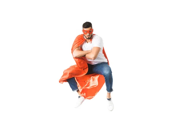 Junger Mann in rotem Mantel und Maske springt mit verschränkten Armen und blickt vereinzelt in die Kamera — Stockfoto