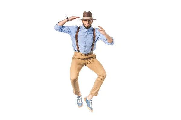 Stylish young man in hat jumping and looking at camera isolated on white — Stock Photo