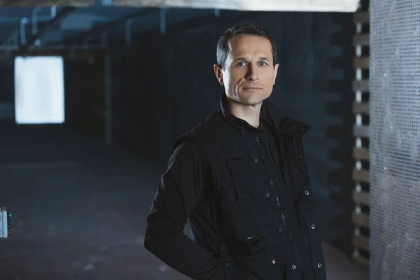 Handsome serious man standing in shooting range and looking at camera — Stock Photo