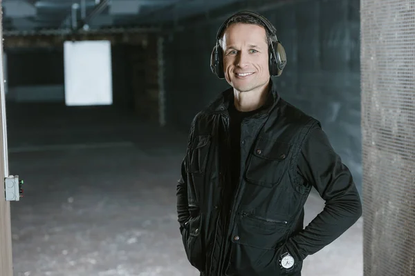 Smiling handsome man looking at camera in shooting range — Stock Photo