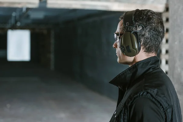 Side view of handsome man looking at target in shooting range — Stock Photo