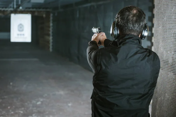 Rear view of man aiming gun at target in shooting range — Stock Photo