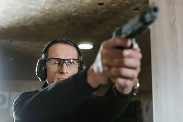 Mann zielt mit Waffe auf Scheibe im Schießstand — Stockfoto