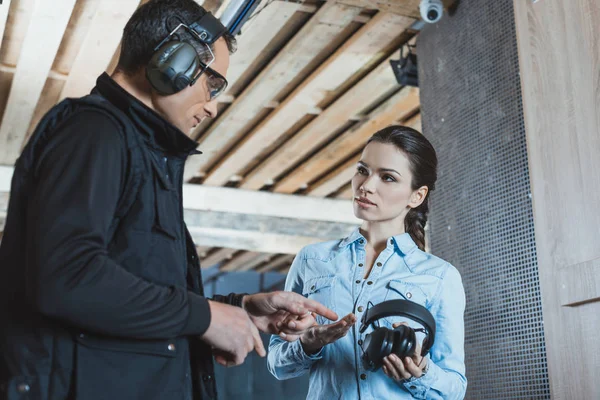 Instructor pointing on ear muffs in shooting range — Stock Photo