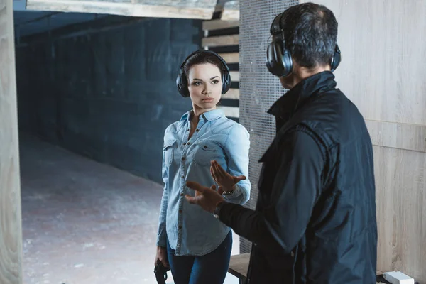 Female customer talking with male instructor in shooting range — Stock Photo