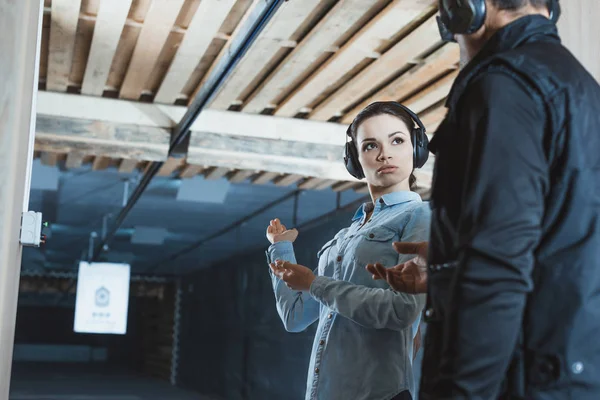 Female customer talking with male instructor in shooting range — Stock Photo