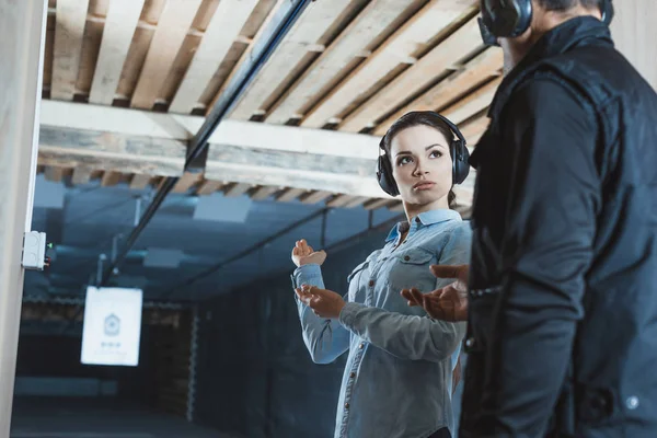 Client féminin parlant avec un instructeur masculin dans le champ de tir — Photo de stock