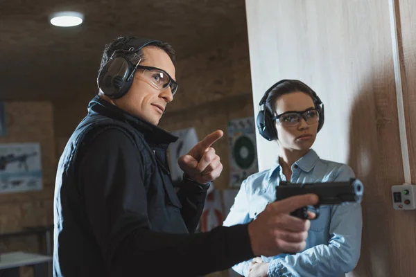 Male instructor pointing on something in shooting gallery — Stock Photo