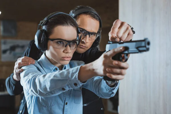 Instructor helping customer in shooting gallery — Stock Photo