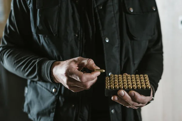 Cropped image of man taking bullet from box — Stock Photo