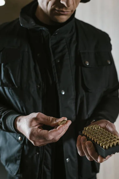 Cropped image of man taking bullet from box — Stock Photo