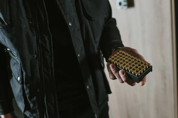 Cropped image of man holding box with bullets — Stock Photo