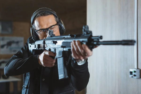 Homem bonito apontando rifle na faixa de tiro — Fotografia de Stock