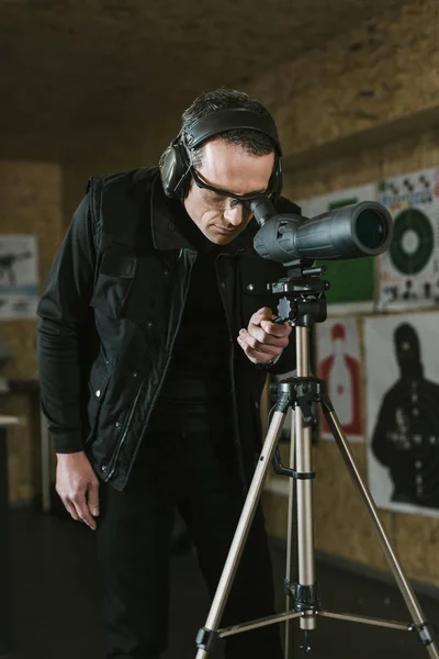 Man looking through binoculars at remote target in shooting range — Stock Photo