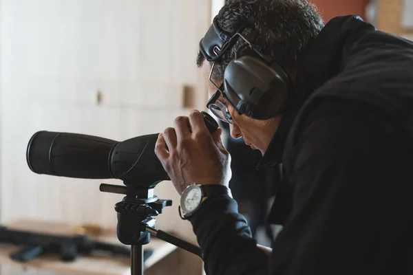 Mann blickt durch Fernglas in Schießstand — Stockfoto