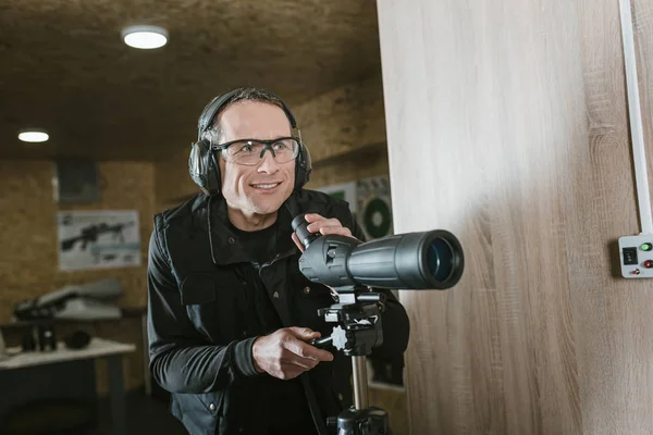 Lächelnder Mann mit Fernglas im Schießstand — Stockfoto